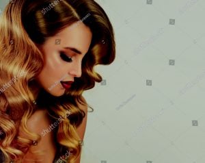 Profile view of a woman with long, wavy hair and makeup, showcasing a hairstyle.