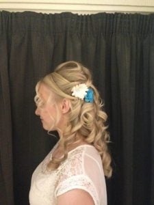 Woman with elegantly styled curly hair adorned with white and blue floral accessories.