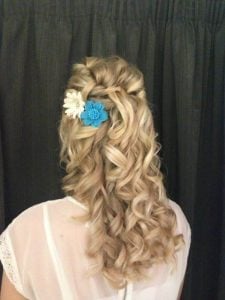 Curly hairstyle adorned with blue and white floral accents, viewed from the back.