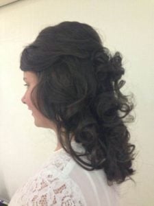 Side view of a woman with a voluminous curly hairstyle featuring defined curls and layered texture.