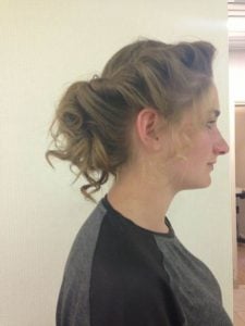 Woman with a curly updo hairstyle, viewed from the side, showcasing defined curls and volume.