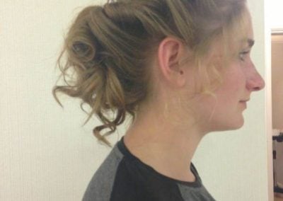 Woman with a curly updo hairstyle, viewed from the side, showcasing defined curls and volume.