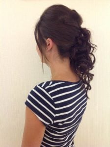 Curly updo hairstyle styled on a woman with long hair, viewed from the back.