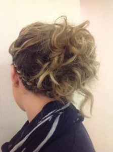 Curly updo hairstyle with loose curls and a braided section at the back.