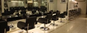 Interior view of a hair salon showing styling stations with black chairs and mirrors.