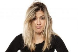 A woman with messy, unkempt hair and a neutral expression, wearing a black top.