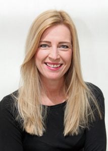Woman with long blonde hair and a black top smiling at the camera.